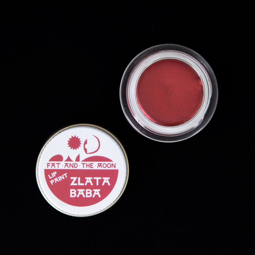 Open jar of Fat and the Moon's "Zlata Baba" lip paint. The glass jar is open, revealing a shimmering true red lip paint.