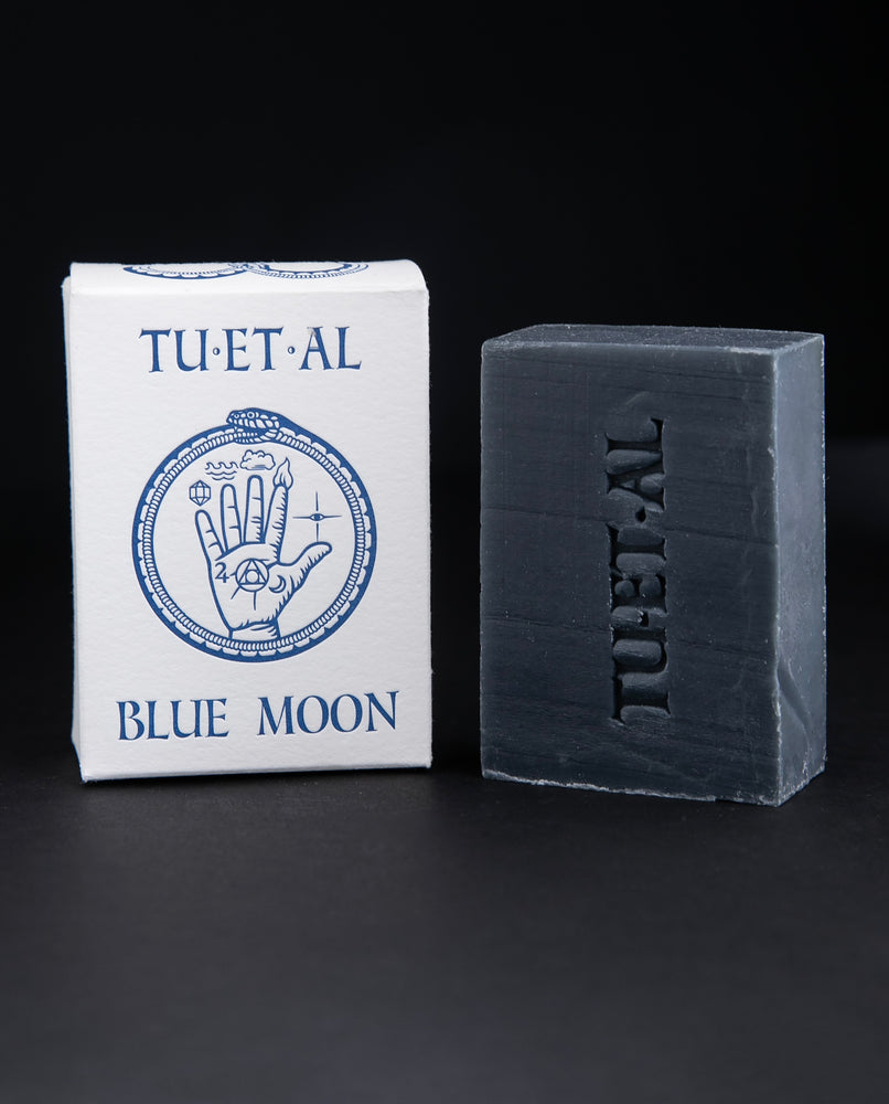 TU-ET-AL's Blue Moon soap next to its white cardboard box against a black background.