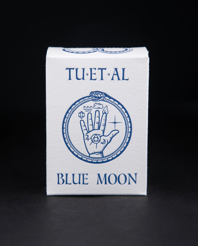 White cardboard soap box containing TU-ET-AL's "Blue Moon" soap. There is an illustration of a snake eating it's own tail, and an alchemical hand on front in blue.