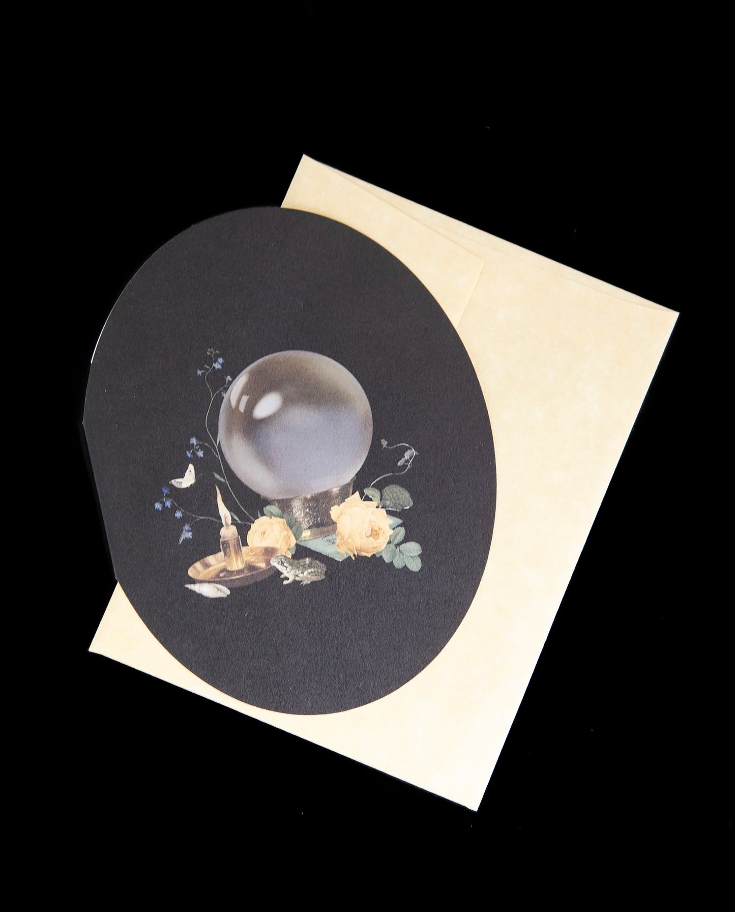 oval shaped crystal ball card sitting atop its cream-coloured envelope