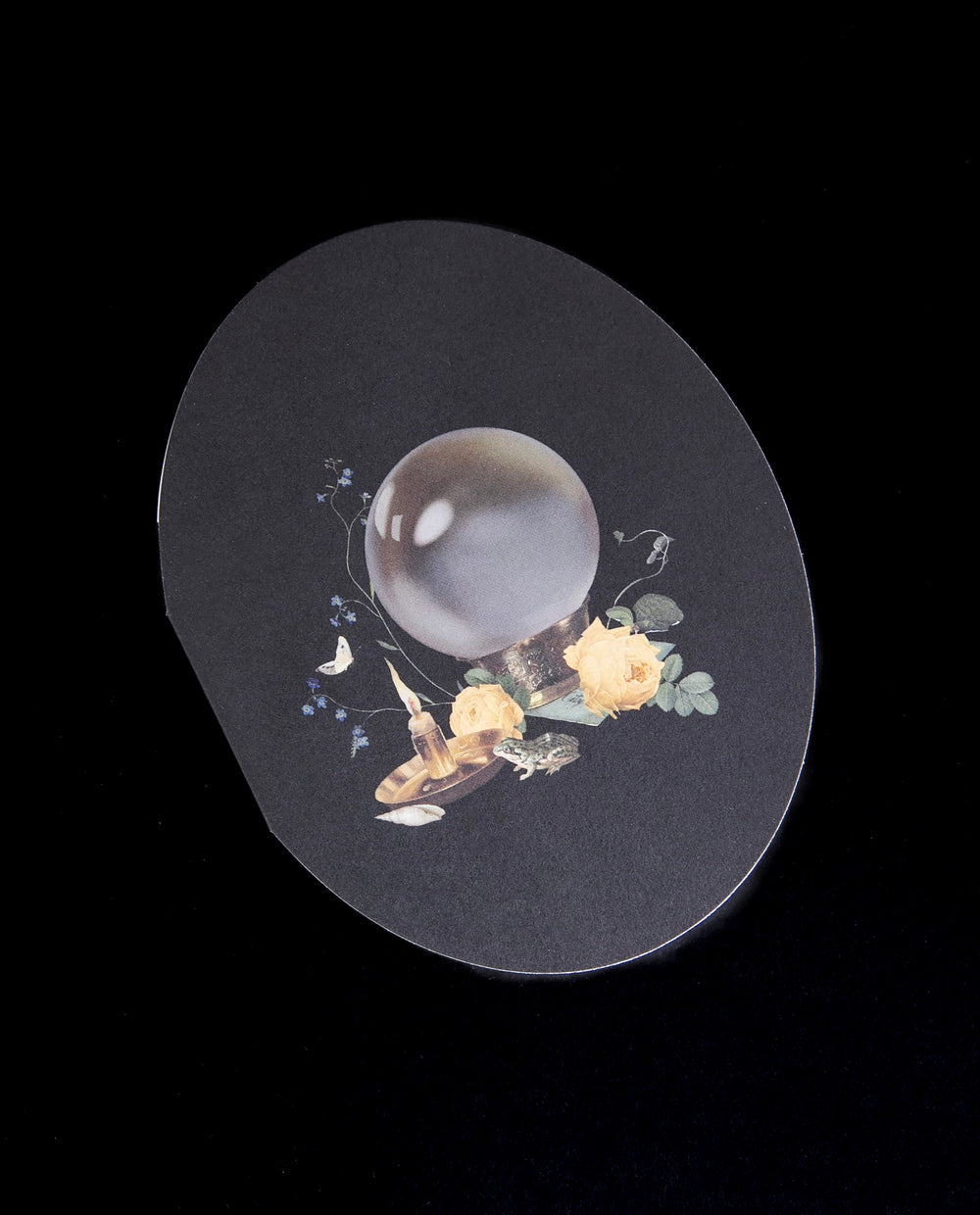 black oval shaped card with illustration of a crystal ball, seen against a black background