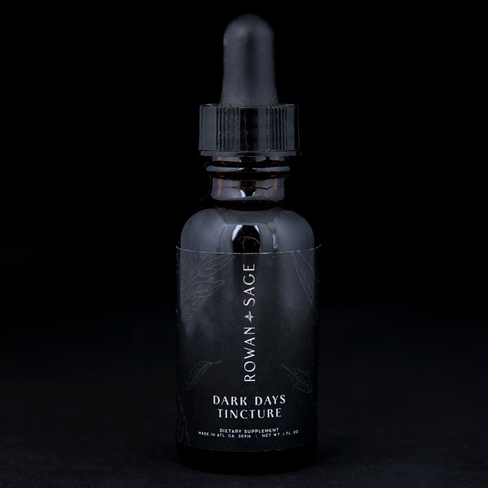 1oz amber glass bottle with dropper top and black label, containing Rown + Sage's "Dark Days" tincture on black background.