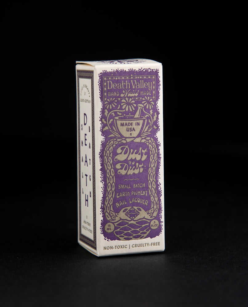 Box for "Dust to Dust" collection nail polishes. The box is cream-coloured with a purple vintage-style illustration of a mortar and pestle, and two snakes