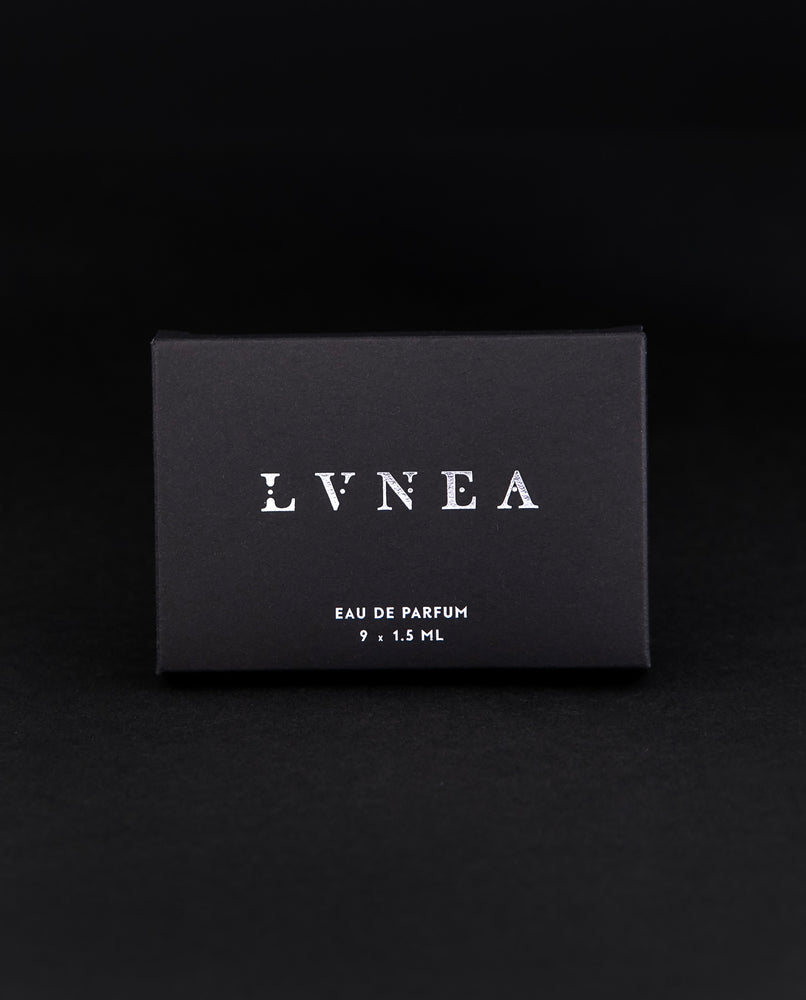 All 9 LVNEA eau de parfum samples peeking out from their black coardboard box, printed with silver foil