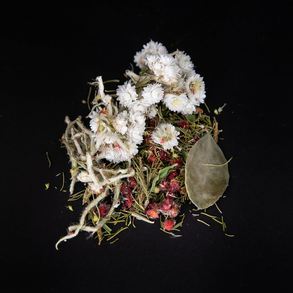 Handful of loose leaf "Été nordique" tea on a black background. The blend features sumac berries and whole imortelle flowers.