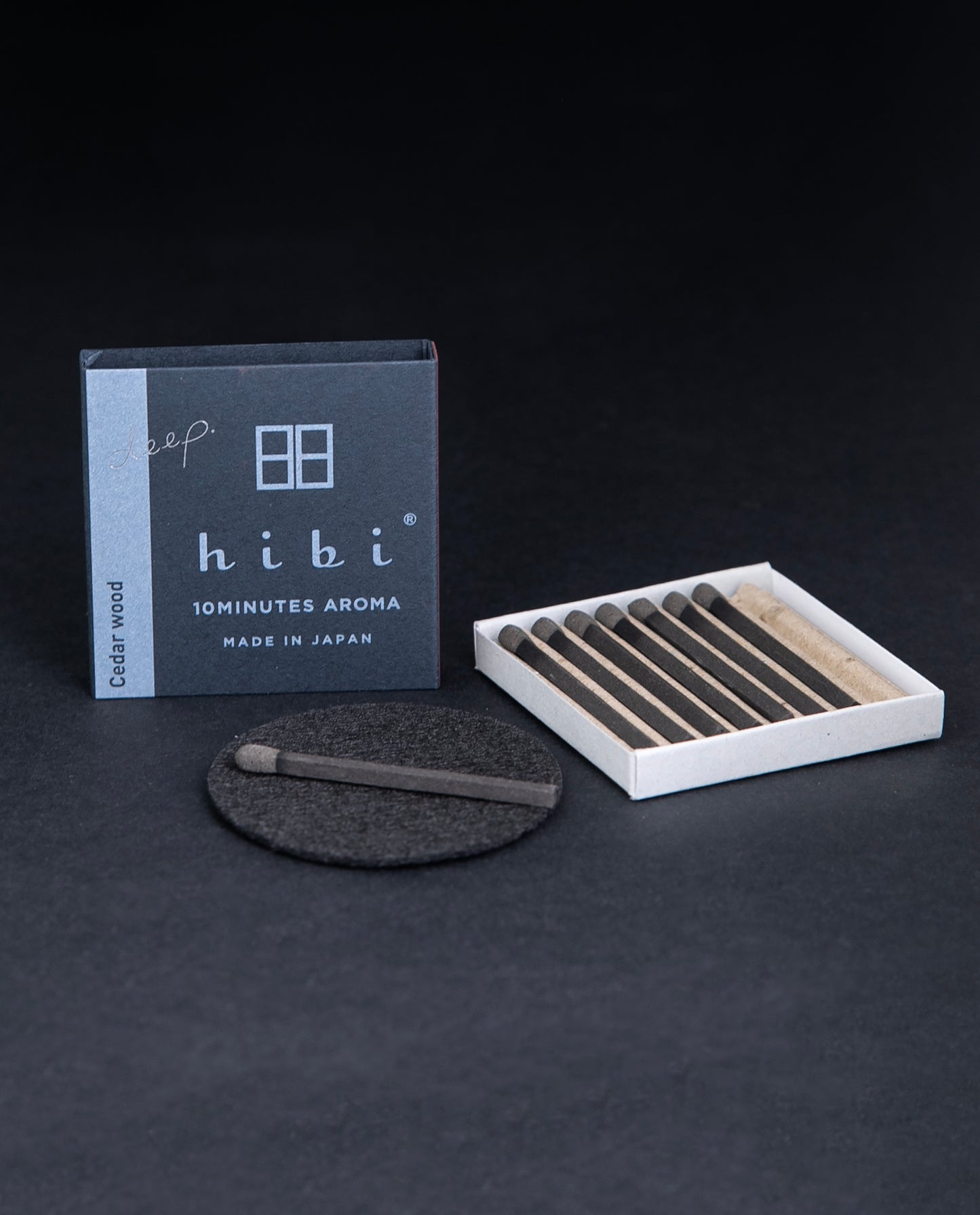 open box of HIBI incense matches, individual matches are nestled in a corrugated cardboard insert, a match is sitting on a small heatproof burn mat