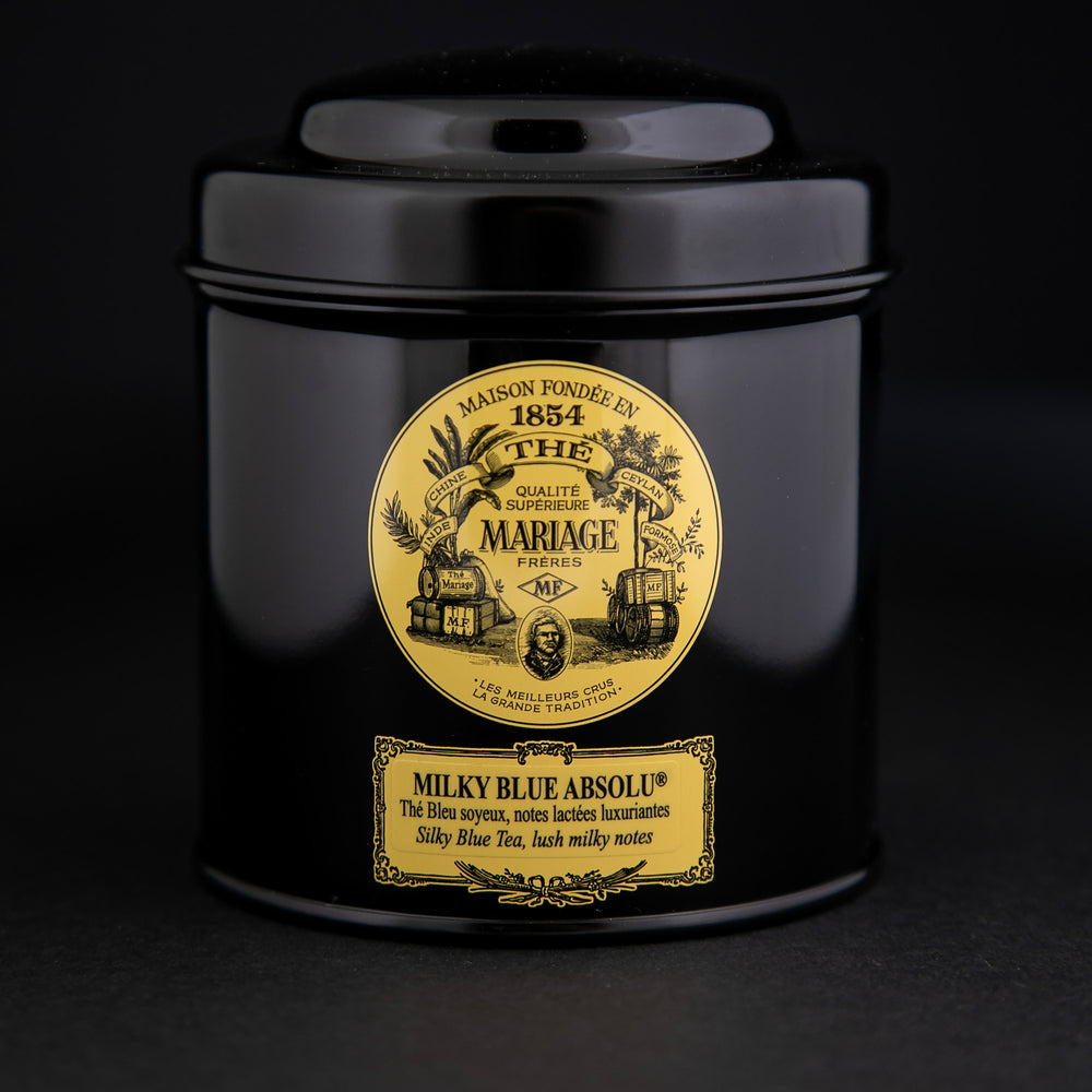 100g black laquered metal canister of Mariage Frère's "Milky Blue Absolu" tea blend on black background.