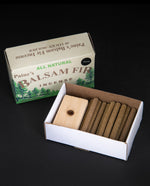 Open box of Paine's Balsam Fir incense logs on black background