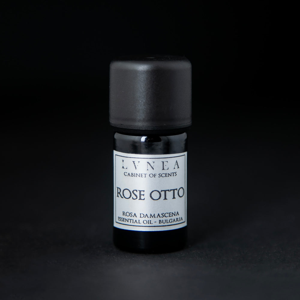 5ml black glass bottle of LVNEA's rose otto essential oil on black background