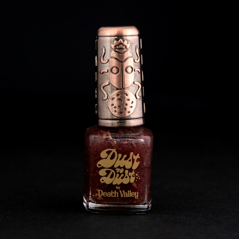 Bottle of "wildflowers" nail polish. The polish base is clear, with flecks of deep pink wildflower petals mixed throughout.