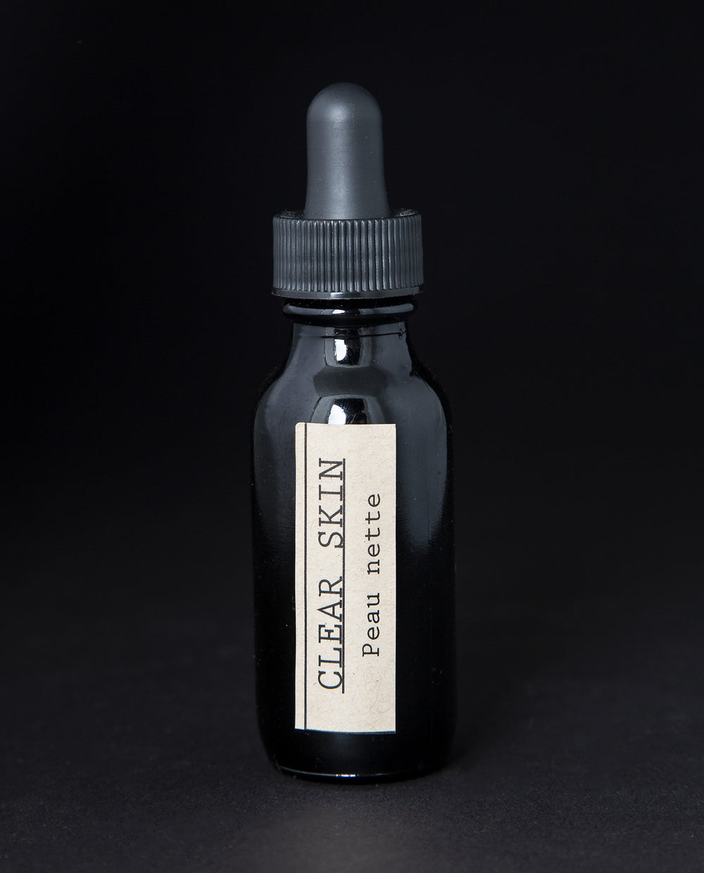 black glass bottle with black dropper top and tan label reading 