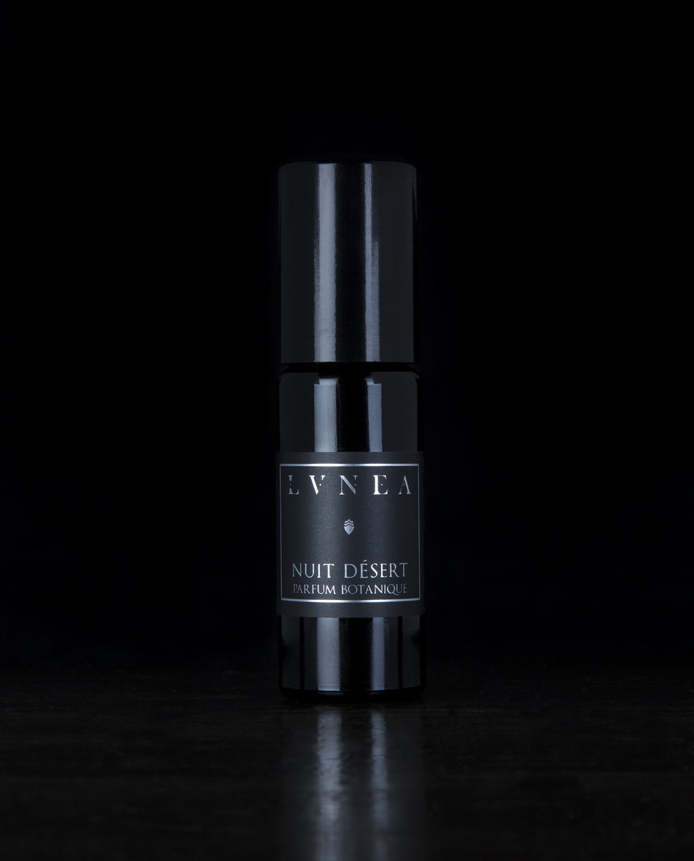 10ml black glass bottle of LVNEA's Nuit Désert natural roll on perfume oil on black background