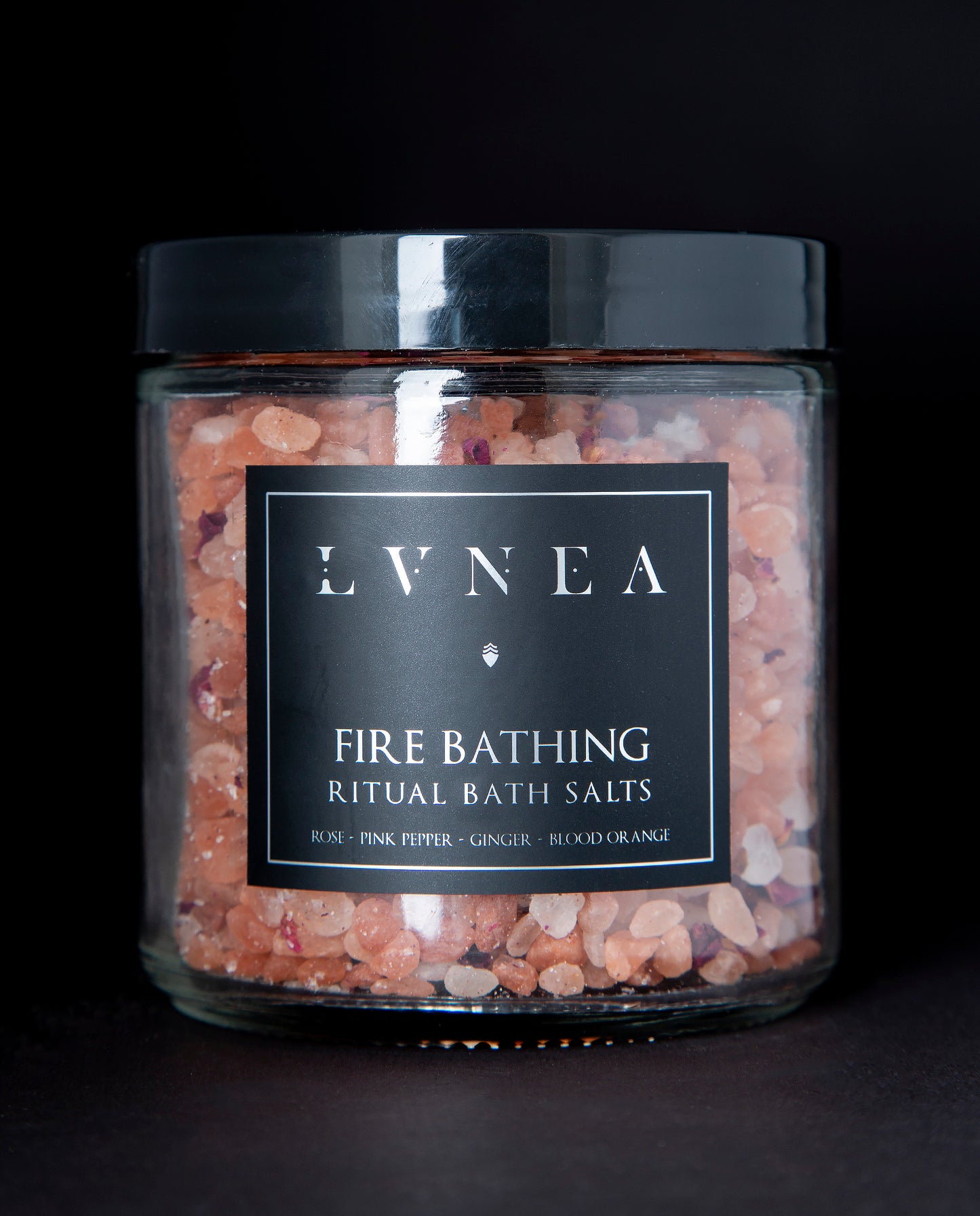 A clear 16 ounce jar filled with LVNEA's Fire Bathing bath salts on black background