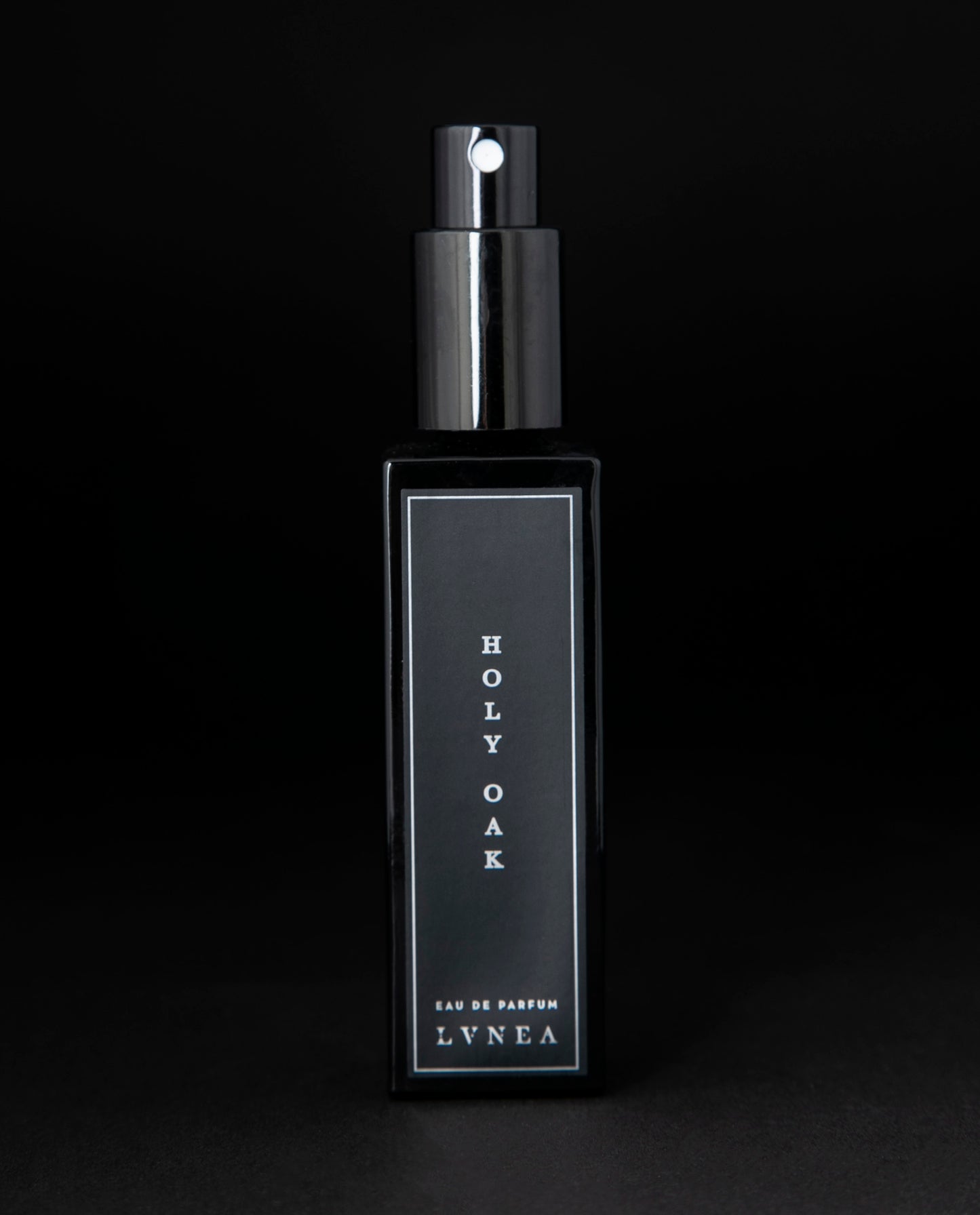 30ml black glass bottle of LVNEA’s Holy Oak natural perfume on black background. The lid is removed, exposing the bottle's spray top.