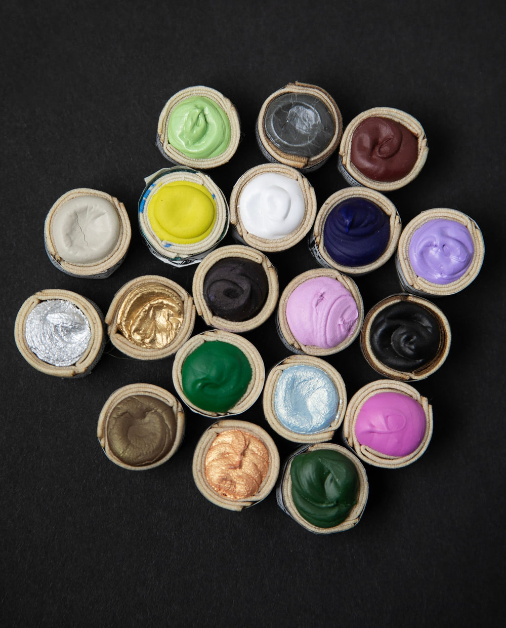 A colourful array of Beam Paints' watercolour paintstones against a black background.